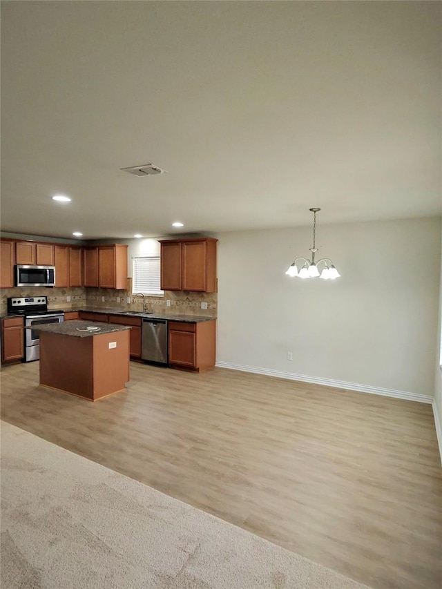 3116 Montserrat Creek Dr, Little Elm, TX 75068 - kitchen with stainless steel appliances, tasteful backsplash, a center island, dark countertops, and a chandelier