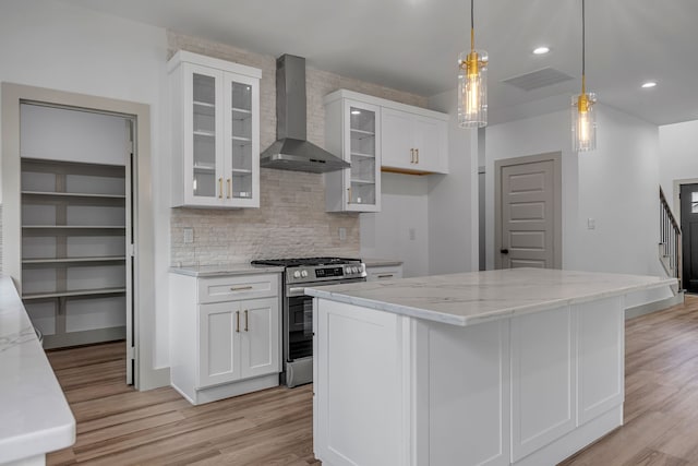 3709 Colonial Ave, Dallas, TX 75215 - kitchen with wall chimney range hood, stainless steel gas range oven, light wood-style flooring, light stone countertops, and white cabinetry
