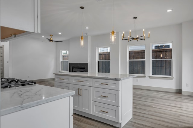 3709 Colonial Ave, Dallas, TX 75215 - kitchen featuring gas cooktop, a chandelier, white cabinetry, light wood-type flooring, and a fireplace