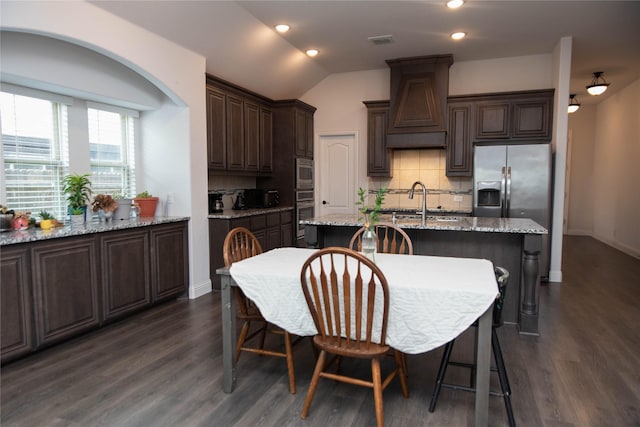 4333 Old Timber Ln, Fort Worth, TX 76036 - kitchen featuring custom range hood, dark brown cabinetry, appliances with stainless steel finishes, decorative backsplash, and a kitchen island with sink