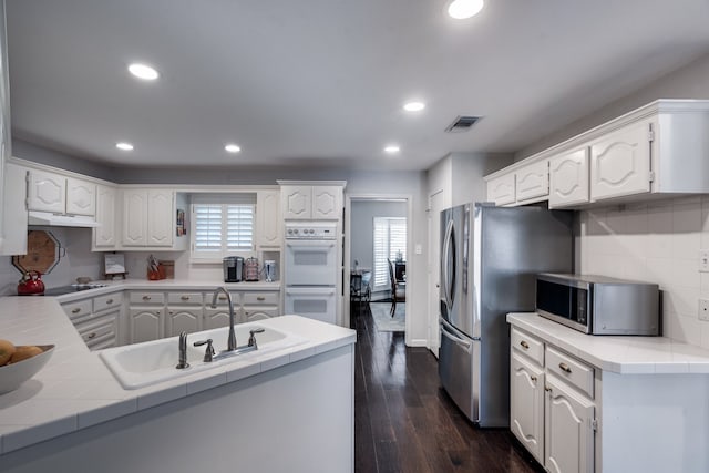 2313 Parkhaven Dr, Plano, TX 75075 - kitchen with stainless steel appliances, under cabinet range hood, dark wood-type flooring, white cabinets, and recessed lighting
