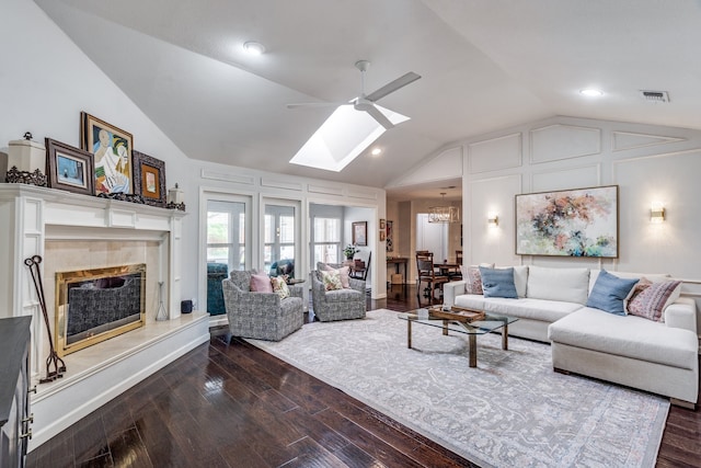 2313 Parkhaven Dr, Plano, TX 75075 - living room with lofted ceiling, a skylight, a ceiling fan, a tiled fireplace, and dark wood finished floors