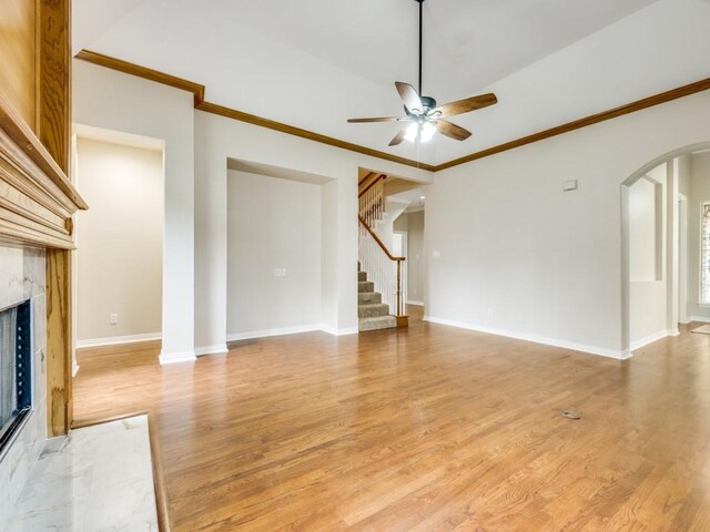 564 Austin Ct, Coppell, TX 75019 - unfurnished living room featuring ceiling fan, a premium fireplace, arched walkways, ornamental molding, and light wood-type flooring