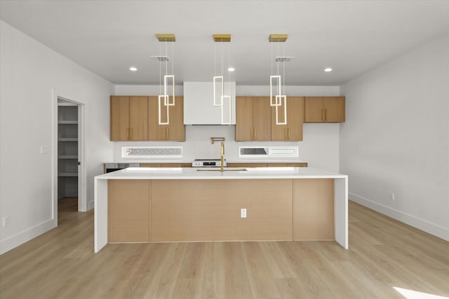 3434 Puget St, Dallas, TX 75212 - kitchen featuring light countertops, light wood finished floors, a kitchen island with sink, recessed lighting, and brown cabinetry