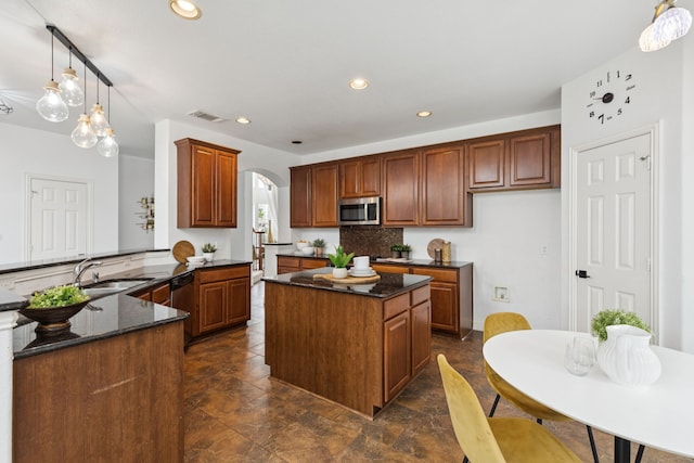 5312 Ridgeson Dr, Mckinney, TX 75071 - kitchen featuring appliances with stainless steel finishes, a center island, arched walkways, recessed lighting, and dark stone countertops