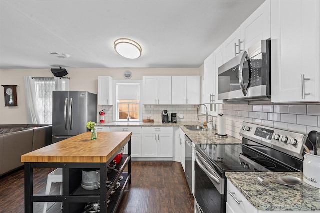 4204 Geddes Ave, Fort Worth, TX 76107 - kitchen with stainless steel appliances, dark wood finished floors, white cabinets, tasteful backsplash, and light stone counters