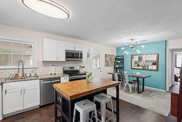 4204 Geddes Ave, Fort Worth, TX 76107 - kitchen with appliances with stainless steel finishes, butcher block counters, dark wood-style floors, and decorative backsplash