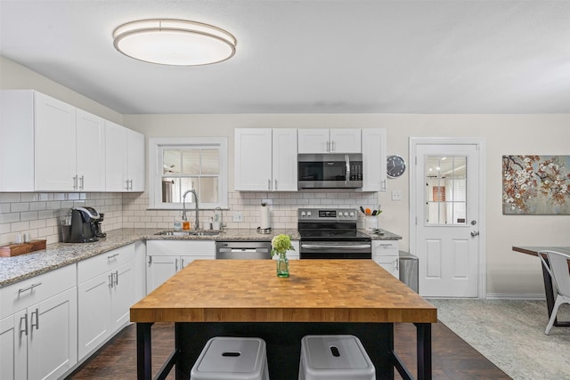 4204 Geddes Ave, Fort Worth, TX 76107 - kitchen featuring appliances with stainless steel finishes, a kitchen breakfast bar, decorative backsplash, and white cabinets
