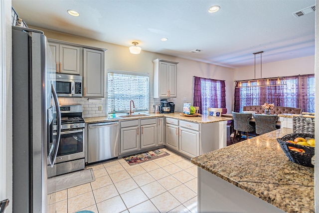 1617 Wood Ridge Ct, Corinth, TX 76210 - kitchen with appliances with stainless steel finishes, a peninsula, gray cabinets, light tile patterned flooring, and backsplash