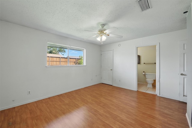 2015 Shenandoah Dr, Carrollton, TX 75007 - unfurnished bedroom featuring light wood-style flooring, a textured ceiling, ensuite bathroom, and a ceiling fan