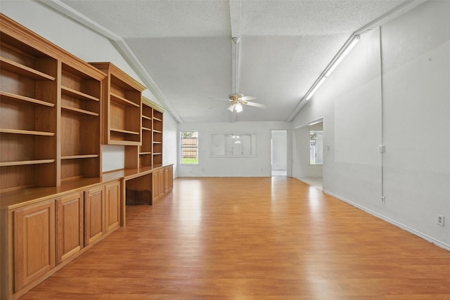 2015 Shenandoah Dr, Carrollton, TX 75007 - unfurnished living room with light wood-style floors, built in study area, a ceiling fan, lofted ceiling, and a textured ceiling