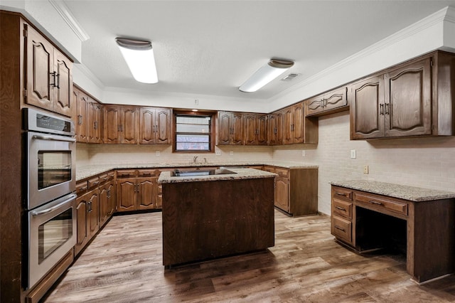 1632 Andy Dr, Sherman, TX 75092 - kitchen with double oven, decorative backsplash, wood finished floors, ornamental molding, and a center island