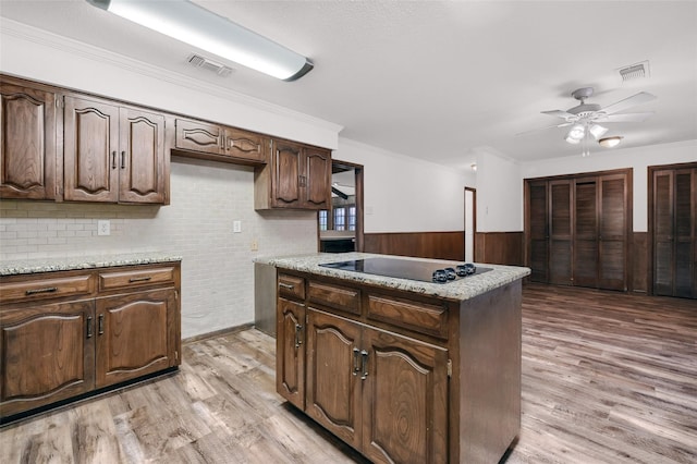 1632 Andy Dr, Sherman, TX 75092 - kitchen with light wood-style floors, a ceiling fan, wainscoting, black electric cooktop, and wood walls