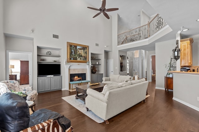 5820 Woodwind Dr, Plano, TX 75093 - living area with built in shelves, a ceiling fan, a lit fireplace, dark wood finished floors, and a high ceiling
