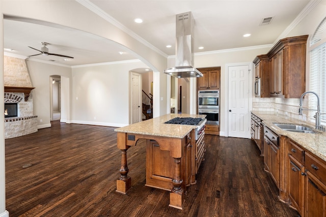 11560 Mirage Ln, Frisco, TX 75033 - kitchen with island exhaust hood, appliances with stainless steel finishes, open floor plan, a ceiling fan, and light stone counters