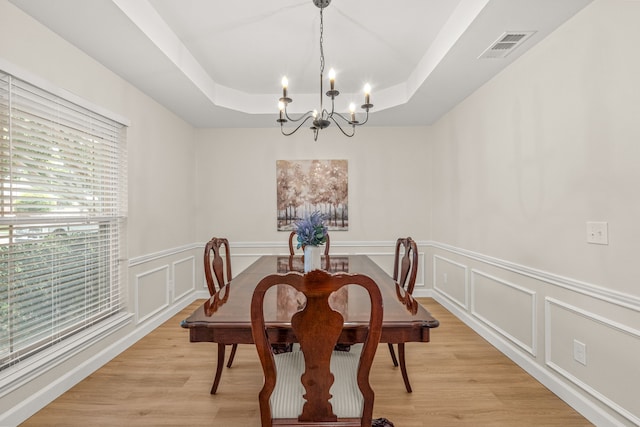 2305 Delmar Dr, Plano, TX 75075 - dining area featuring a tray ceiling, a chandelier, a decorative wall, light wood finished floors, and a wainscoted wall