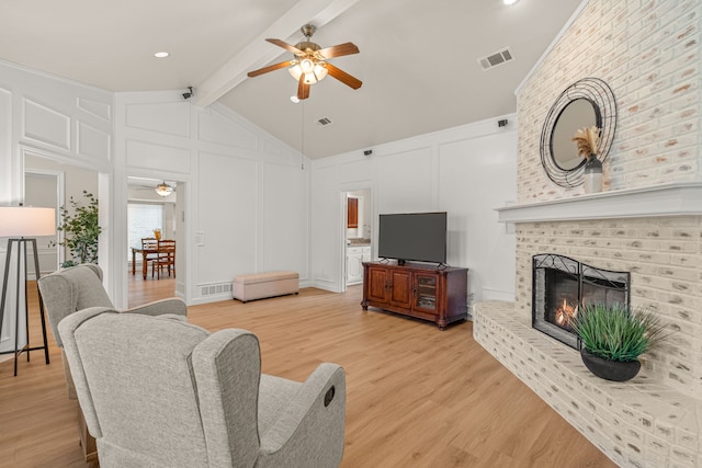 2305 Delmar Dr, Plano, TX 75075 - living room featuring a decorative wall, a ceiling fan, a fireplace, and light wood-style flooring