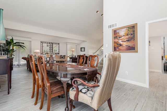 6141 Prestondell Ct, Dallas, TX 75240 - dining area with stairway, light wood finished floors, and a towering ceiling