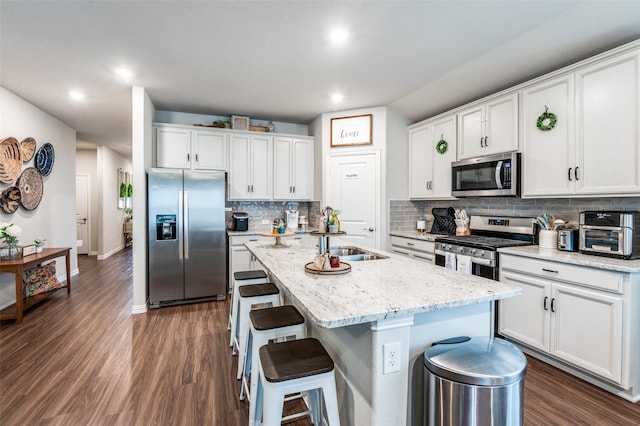 2805 Field St, Celina, TX 75009 - kitchen featuring appliances with stainless steel finishes, dark wood finished floors, a kitchen island with sink, white cabinets, and decorative backsplash