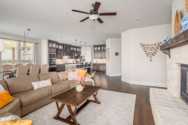 1251 Castle Dr, Prosper, TX 75078 - living room featuring a ceiling fan, a chandelier, dark wood finished floors, and a stone fireplace