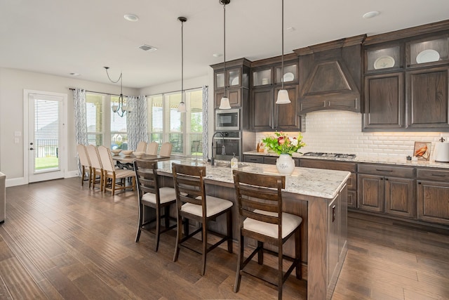 1251 Castle Dr, Prosper, TX 75078 - kitchen featuring premium range hood, decorative backsplash, dark brown cabinets, appliances with stainless steel finishes, and dark wood-style flooring