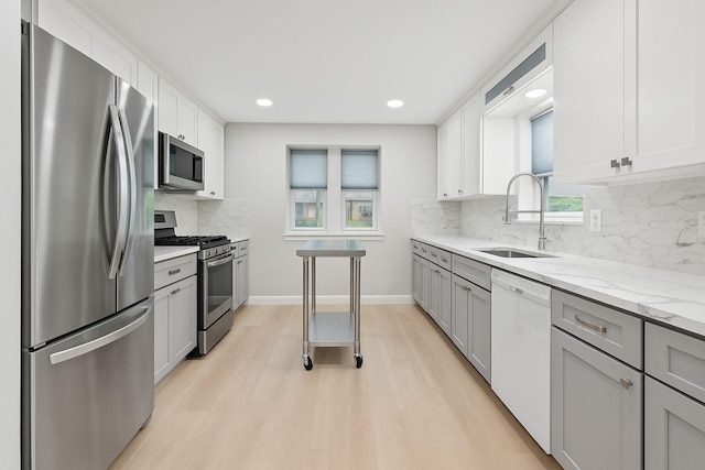 1301 Warwick St, Garland, TX 75040 - kitchen featuring appliances with stainless steel finishes, light wood-style floors, backsplash, light stone counters, and gray cabinets