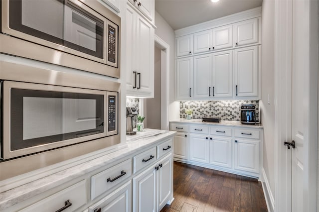 3791 Marble Hill Rd, Frisco, TX 75034 - kitchen featuring stainless steel microwave, dark wood-style flooring, white cabinets, and decorative backsplash