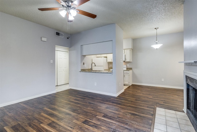 9747 Whitehurst Dr Unit 150, Dallas, TX 75243 - unfurnished living room featuring a fireplace, ceiling fan, wood finished floors, and a textured ceiling