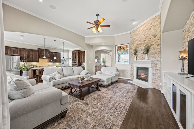 881 Derick Ln, Prosper, TX 75078 - living area featuring arched walkways, a fireplace with flush hearth, ceiling fan, wood finished floors, and crown molding