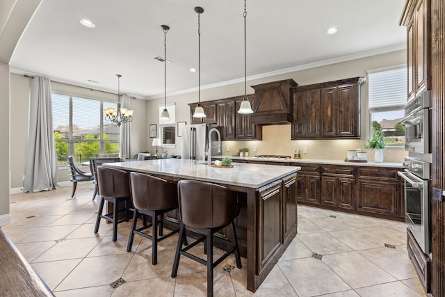 881 Derick Ln, Prosper, TX 75078 - kitchen featuring custom range hood, a breakfast bar area, light tile patterned flooring, a center island with sink, and a chandelier