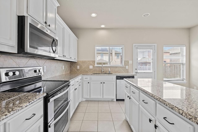 5365 Saba Dr, Fort Worth, TX 76119 - kitchen with stainless steel appliances, tasteful backsplash, white cabinets, light tile patterned floors, and recessed lighting