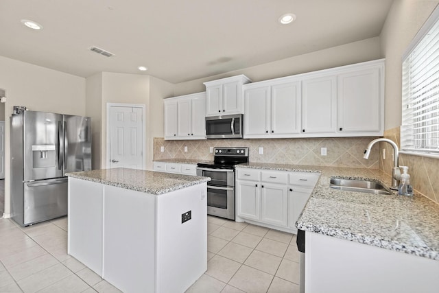 5365 Saba Dr, Fort Worth, TX 76119 - kitchen with appliances with stainless steel finishes, a center island, light tile patterned floors, white cabinets, and recessed lighting