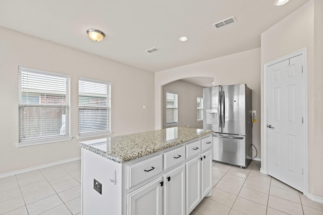 5365 Saba Dr, Fort Worth, TX 76119 - kitchen with stainless steel fridge, arched walkways, light tile patterned floors, light stone countertops, and recessed lighting