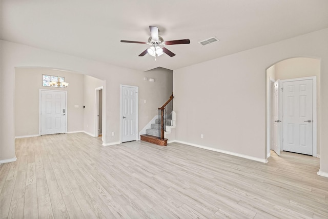 5365 Saba Dr, Fort Worth, TX 76119 - unfurnished living room featuring arched walkways, stairway, light wood-style floors, and ceiling fan
