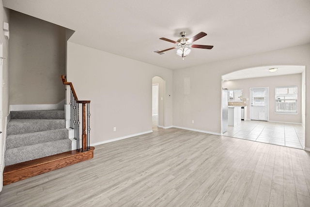 5365 Saba Dr, Fort Worth, TX 76119 - unfurnished living room with arched walkways, ceiling fan, light wood-type flooring, and stairway