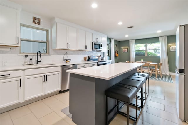 4912 Odessa Ave, Fort Worth, TX 76133 - kitchen featuring appliances with stainless steel finishes, a kitchen bar, decorative backsplash, a center island, and white cabinetry