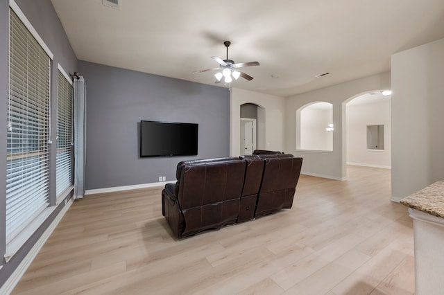 8225 Courtney Way, Watauga, TX 76148 - living area featuring arched walkways, light wood finished floors, and a ceiling fan
