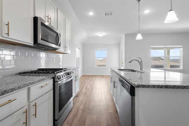 6112 Fall Creek Ln, Fort Worth, TX 76123 - kitchen with stainless steel appliances, light wood-style floors, tasteful backsplash, stone counters, and an island with sink