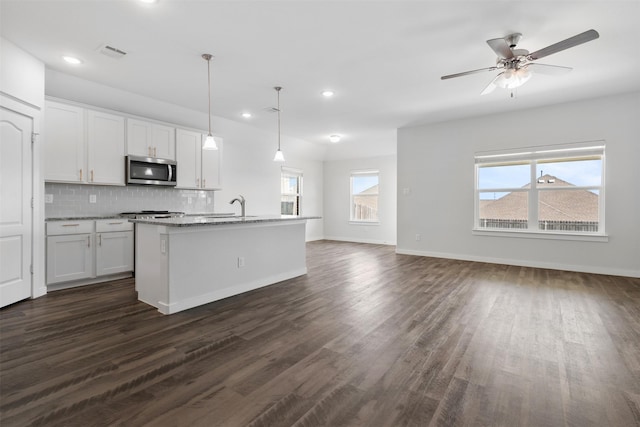 6112 Fall Creek Ln, Fort Worth, TX 76123 - kitchen featuring stainless steel microwave, dark wood-type flooring, backsplash, white cabinetry, and open floor plan