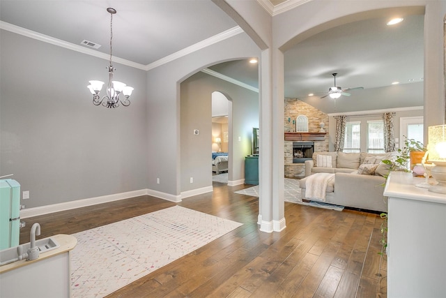 201 Saxon St, Waxahachie, TX 75165 - foyer with ceiling fan, a stone fireplace, dark wood finished floors, crown molding, and arched walkways