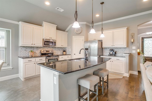 201 Saxon St, Waxahachie, TX 75165 - kitchen featuring stainless steel appliances, a breakfast bar, tasteful backsplash, crown molding, and an island with sink