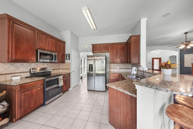 905 Austin Acre, Sulphur Springs, TX 75482 - kitchen with stainless steel appliances, arched walkways, a peninsula, decorative backsplash, and light tile patterned floors