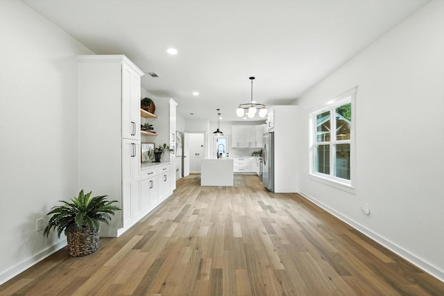 826 W Canty St, Dallas, TX 75208 - kitchen with freestanding refrigerator, open shelves, light wood-style floors, a center island with sink, and light countertops