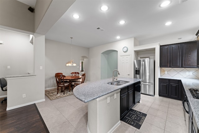 209 Willet Ct, Little Elm, TX 75068 - kitchen featuring black appliances, arched walkways, an island with sink, light stone countertops, and recessed lighting