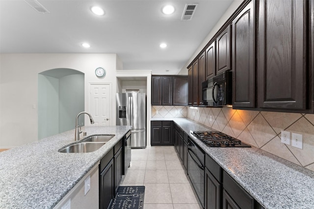 209 Willet Ct, Little Elm, TX 75068 - kitchen with black appliances, arched walkways, backsplash, recessed lighting, and light stone countertops