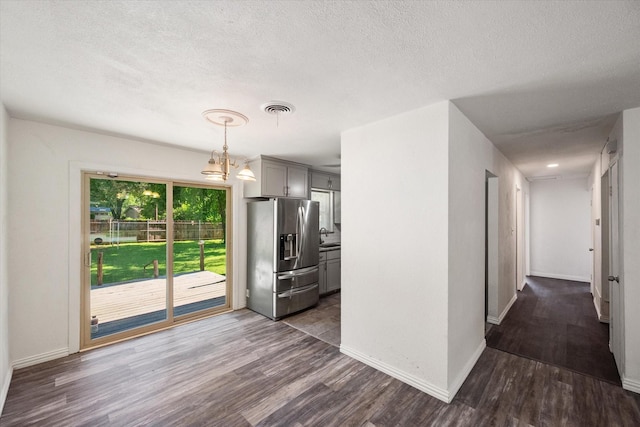612 Elm St, Hurst, TX 76053 - kitchen with stainless steel fridge, gray cabinetry, dark wood-style flooring, a textured ceiling, and a chandelier