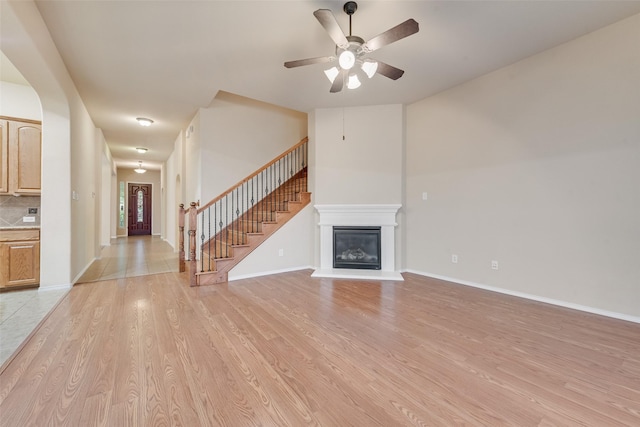 505 Glacier St, Desoto, TX 75115 - unfurnished living room featuring light wood-type flooring, stairway, a ceiling fan, and a glass covered fireplace