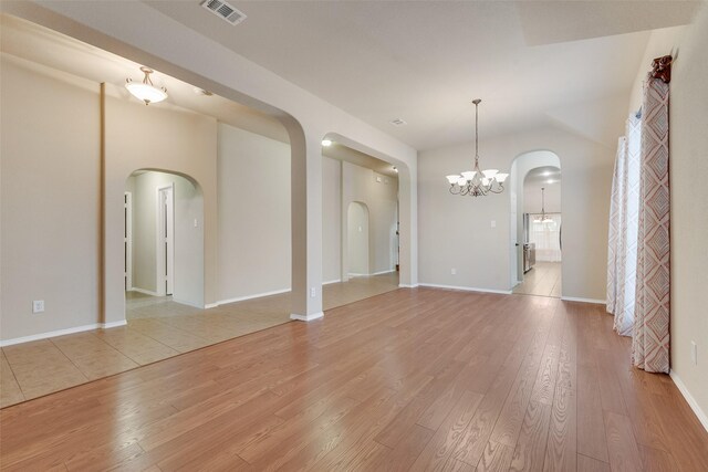 505 Glacier St, Desoto, TX 75115 - unfurnished living room with arched walkways, light wood finished floors, and a chandelier