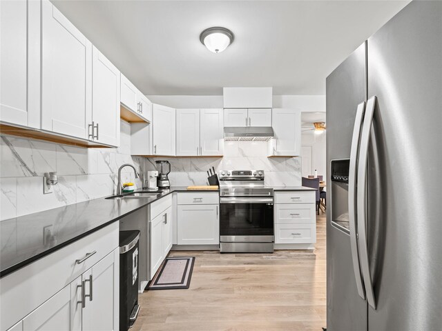 4235 Bonnie View Rd, Dallas, TX 75216 - kitchen featuring stainless steel appliances, under cabinet range hood, decorative backsplash, light wood-style floors, and white cabinets