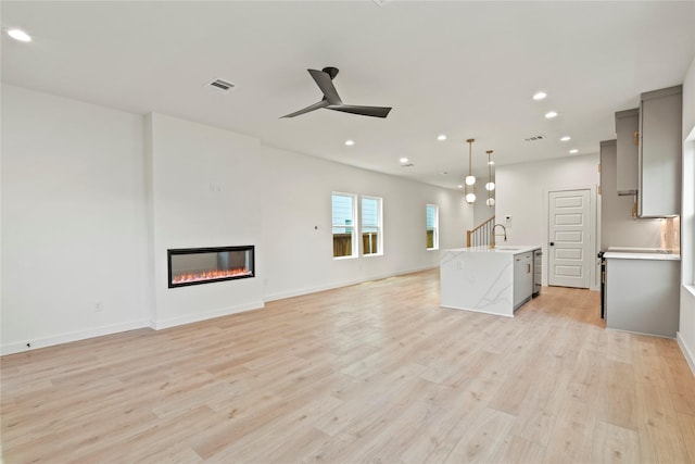 420 N Moore St, Dallas, TX 75203 - unfurnished living room with a ceiling fan, light wood-style floors, recessed lighting, and a glass covered fireplace